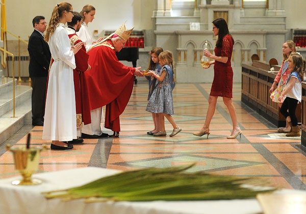 Framed by Palms and a vessel of Holy Water, Bishop Richard Malone accepts the Gifts before Communion at St Joseph Cathedral during Palm Sunday Mass. (Dan Cappellazzo/Staff Photographer)